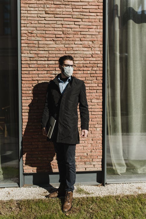 站在棕色砖墙旁边的黑色外套的男人 · 免费素材图片