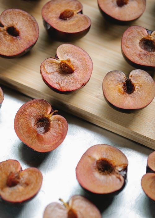 新鲜成熟的一半的红李子，安排在厨房的桌子上 · 免费素材图片