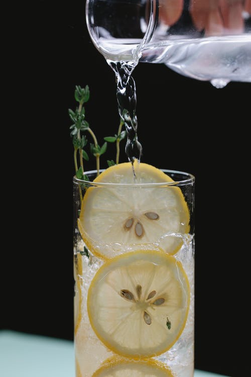 人将液体从玻璃罐倒入玻璃用柠檬 · 免费素材图片