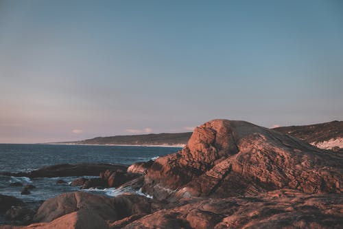 荡漾的海水附近的岩层 · 免费素材图片