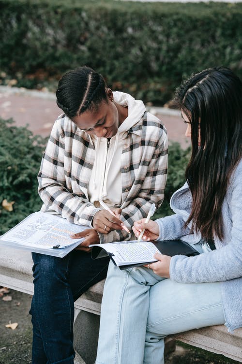 男人和女人坐在长椅上看书 · 免费素材图片