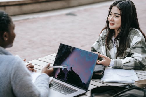 使用黑色便携式计算机的灰色外套的女人 · 免费素材图片