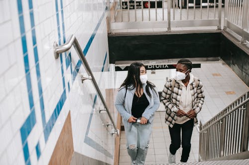 白色和黑色的外套和蓝色牛仔牛仔裤，站在楼梯上的女人 · 免费素材图片