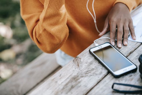 橙色的长袖衬衫，拿着银iphone 6的人 · 免费素材图片