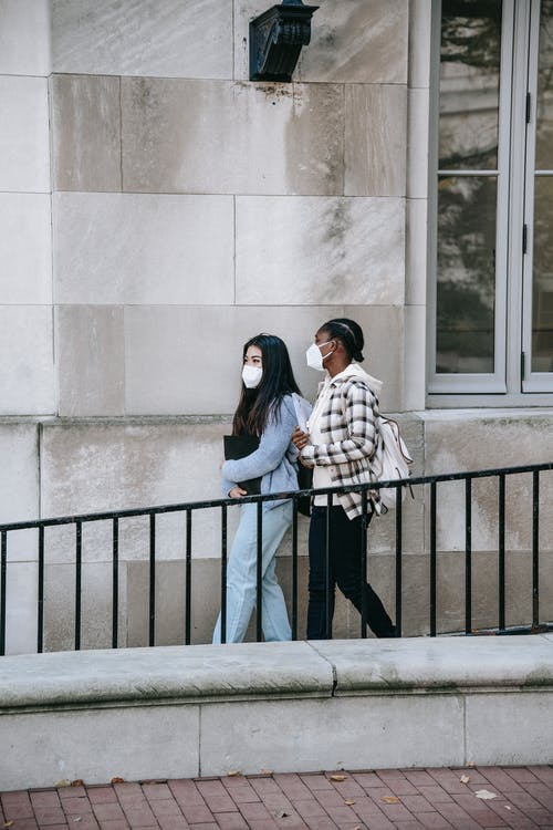 站在黑色金属栅栏旁边的棕色外套的女人 · 免费素材图片