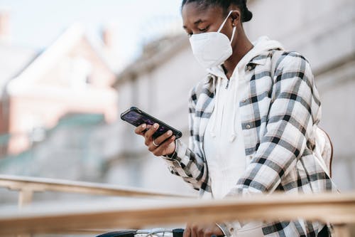 拿着黑色智能手机的白色和黑色格子衬衫的男人 · 免费素材图片