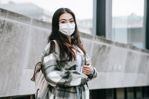 灰色和黑色格子外套覆盖着她的脸与白色面具的女人 · 免费素材图片
