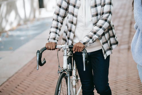 骑自行车的白色和黑色格子衬衫和蓝色牛仔牛仔裤的男人 · 免费素材图片