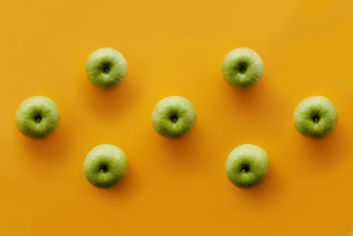 黄色表面上的绿色圆形水果 · 免费素材图片