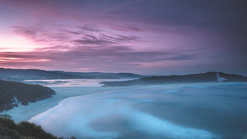 日落时平静的海和山地层 · 免费素材图片