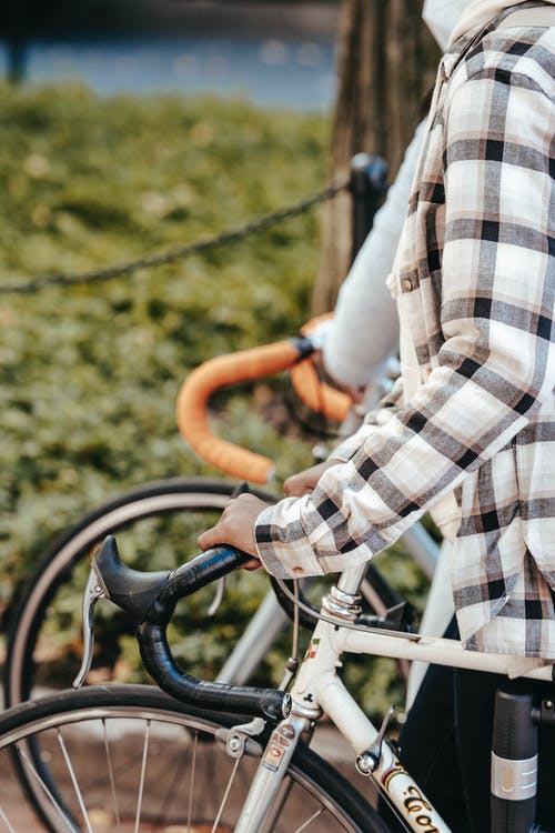 骑自行车的白色黑色和灰色格子长袖衬衫的人 · 免费素材图片
