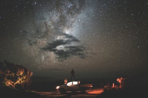 旅行者在繁星闪烁的夜晚站在车上 · 免费素材图片