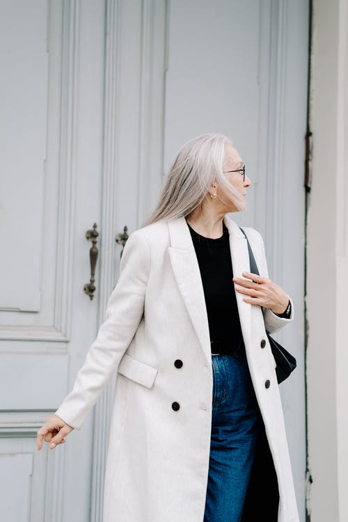 站在白色的木门附近的白色外套的女人 · 免费素材图片