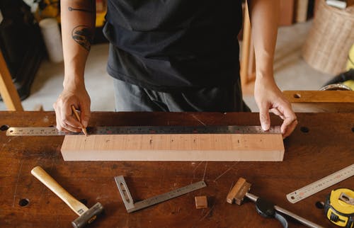 纹身用金属尺测量木板的男人 · 免费素材图片