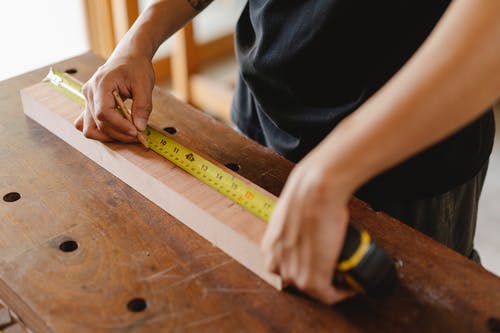 用卷尺测量木板的人 · 免费素材图片