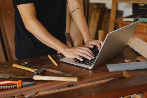 男子检查木材桌上的笔记本电脑上的信息 · 免费素材图片