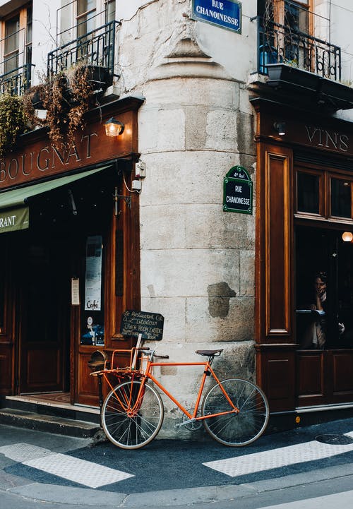 红色城市自行车停在棕色木门旁边 · 免费素材图片