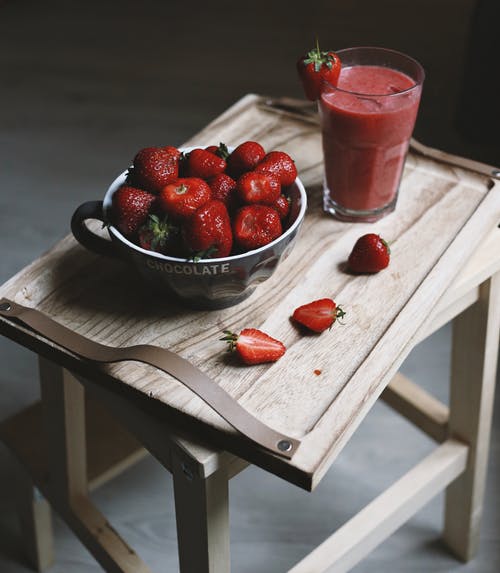 草莓在透明的玻璃碗，棕色木制的桌子上 · 免费素材图片