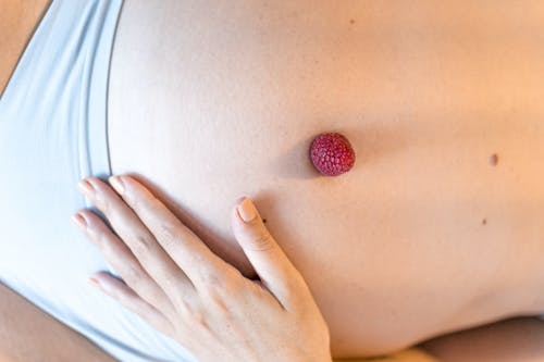 匿名孕妇爱抚腹部与新鲜树莓 · 免费素材图片