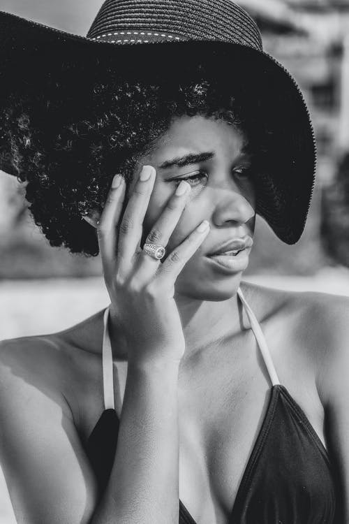 梦幻般的黑人女性，在帽子摸脸 · 免费素材图片