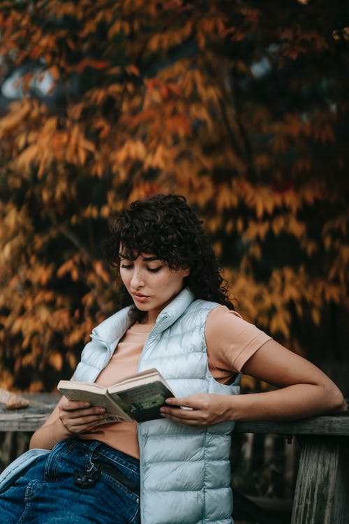 女人看书坐在岩石上 · 免费素材图片