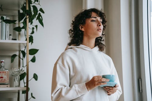 拿着蓝色陶瓷杯子的白色长袖衬衫的女人 · 免费素材图片