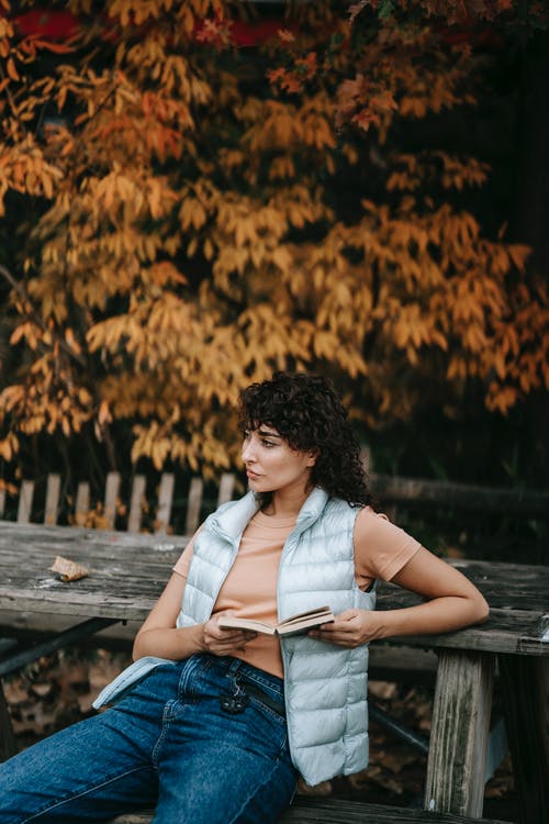 白色无袖衬衫和蓝色牛仔牛仔裤，坐在棕色的木凳上的女人 · 免费素材图片