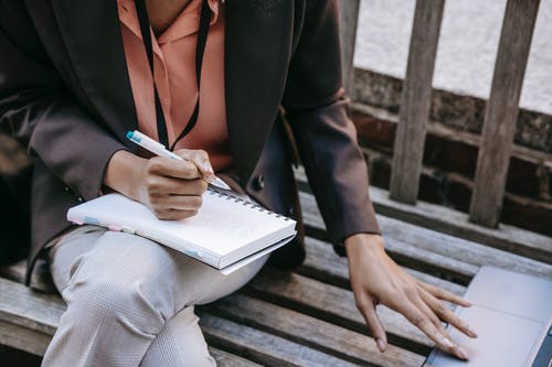 黑色西装外套和白色礼服衬衫握笔和书的女人 · 免费素材图片