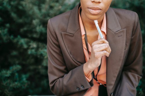 拿着香烟棒的棕色西装外套的女人 · 免费素材图片