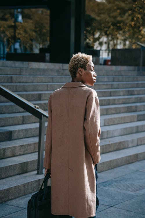 站在灰色的混凝土楼梯上的棕色外套的女人 · 免费素材图片