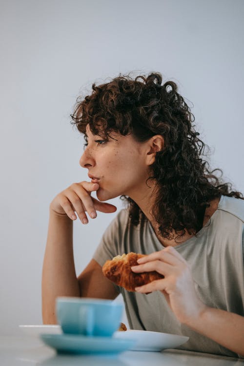 灰色衬衫吃面包的女人 · 免费素材图片