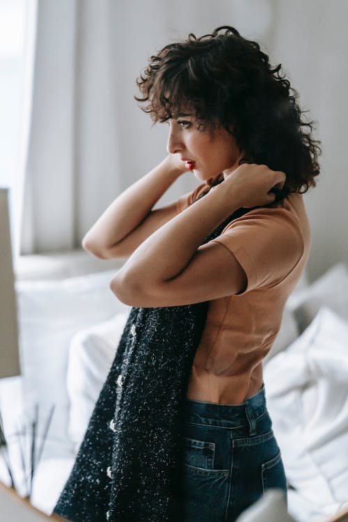 棕色长袖衬衫和蓝色牛仔牛仔裤，坐在白色床上的女人 · 免费素材图片