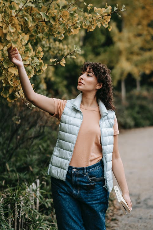 拿着绿色的植物的蓝色牛仔背心的女人 · 免费素材图片