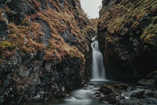 岩石峭壁之间流淌的小瀑布 · 免费素材图片
