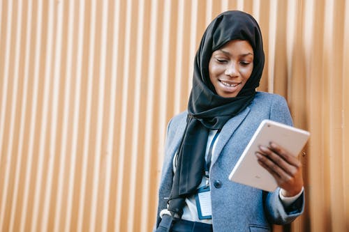 拿着白色片剂计算机的蓝色牛仔布夹克的妇女 · 免费素材图片