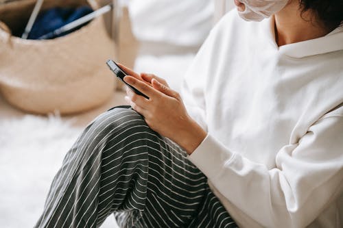 拿着黑色智能手机的白色礼服衬衫的人 · 免费素材图片