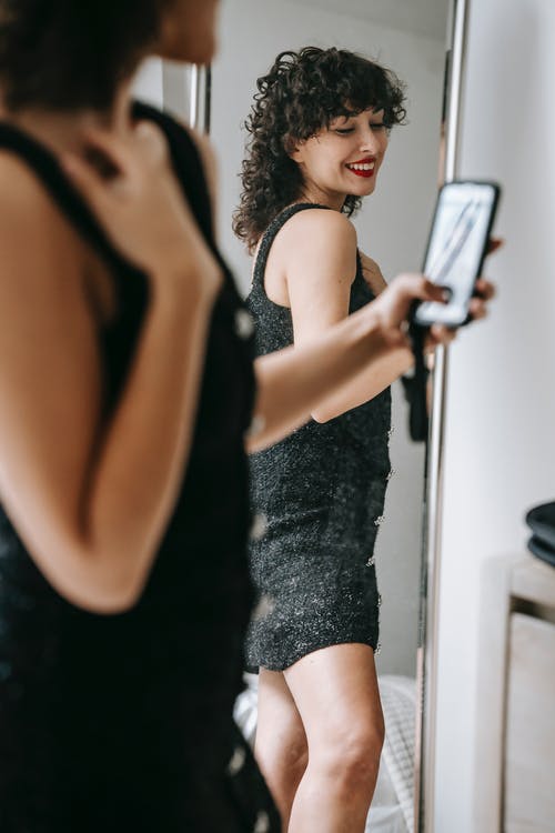 黑色背心和黑色短裤，拿着黑色智能手机的女人 · 免费素材图片