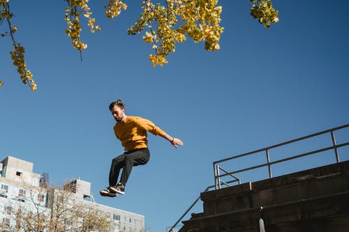 棕色背心和黑色裤子在黑色金属栏杆上跳跃的人 · 免费素材图片