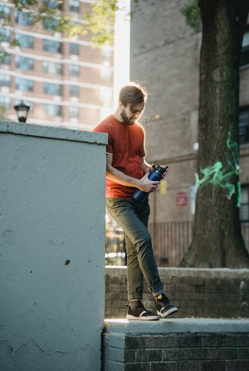 蓝色长袖衬衫和棕色的裤子，拿着黑色的单反相机的人 · 免费素材图片