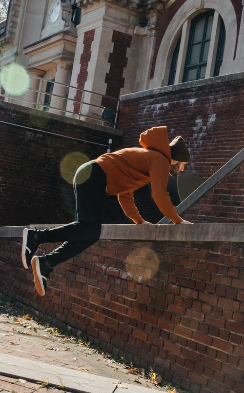 穿棕色夹克和黑色裤子打网球的人 · 免费素材图片