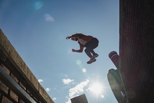 半空中跳跃的黑色外套和蓝色牛仔牛仔裤的男人 · 免费素材图片