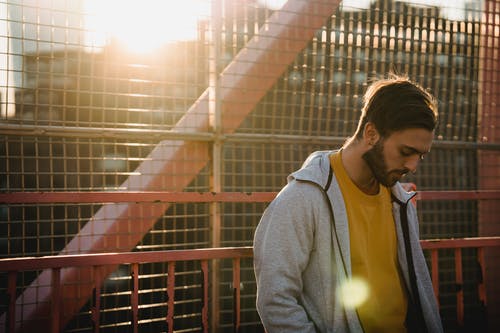 灰色羊毛衫站在棕色金属栅栏附近的女人 · 免费素材图片