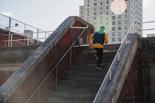 黄色衬衫和黑色的裤子，在灰色的混凝土楼梯上行走的人 · 免费素材图片