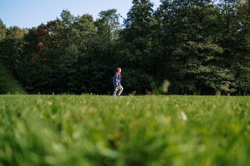 穿着红色衬衫在绿色草地上行走的人 · 免费素材图片