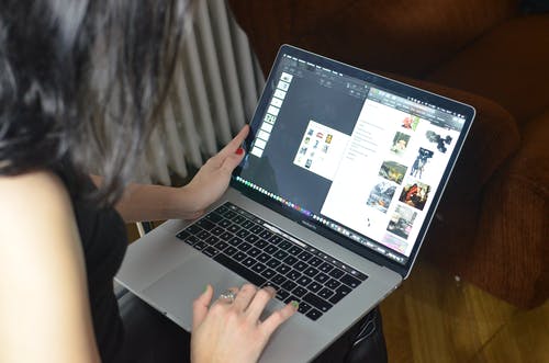 女人在棕色的木桌上使用macbook Pro · 免费素材图片