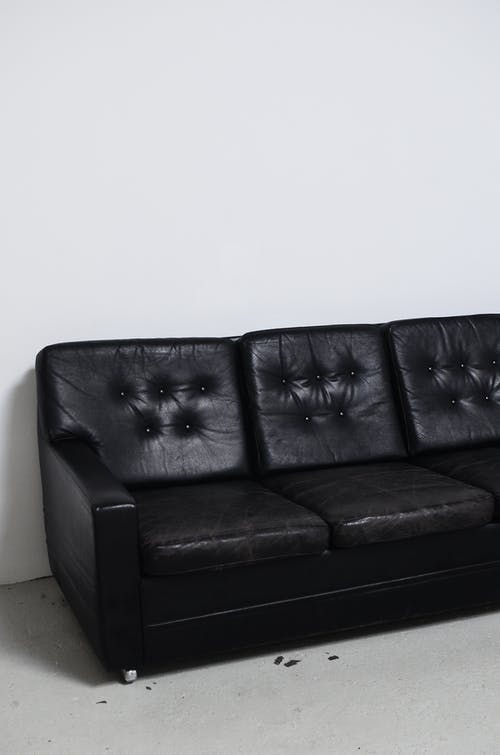 白墙旁的黑色皮革沙发 · 免费素材图片