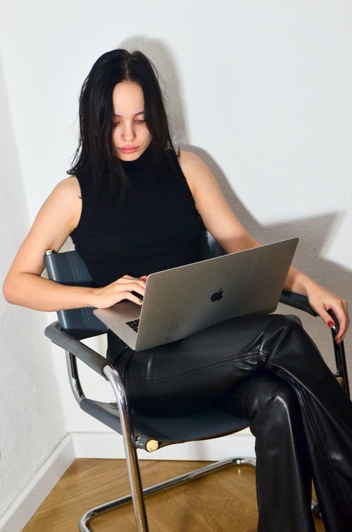 黑色背心坐在椅子上，使用macbook的女人 · 免费素材图片