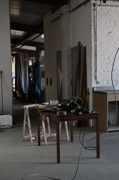 白墙附近的棕色木桌 · 免费素材图片