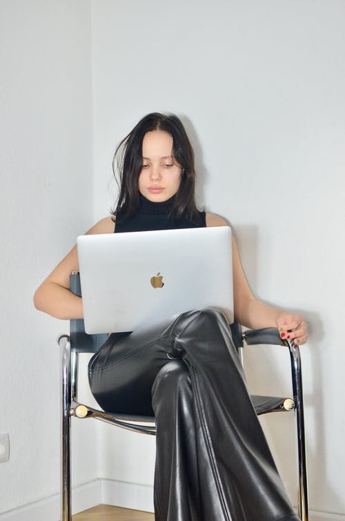 坐在椅子上使用macbook的黑裙子的女人 · 免费素材图片