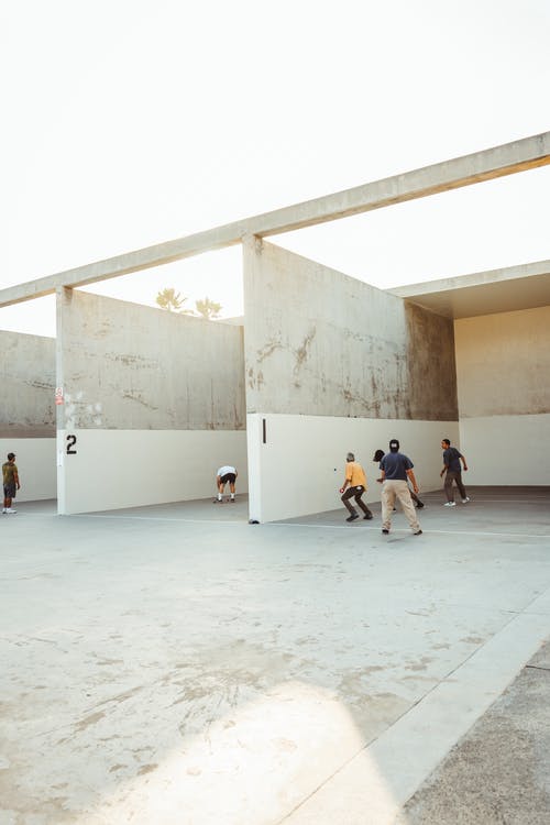 在阳光下在室外球场打手球的匿名运动员 · 免费素材图片